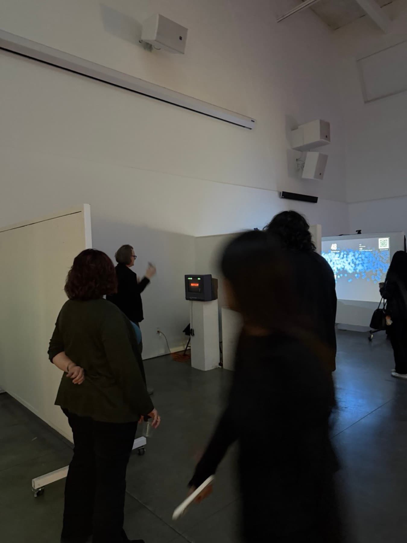 Visitors gathered around the installation during the exhibition, with the piece projected on the far wall